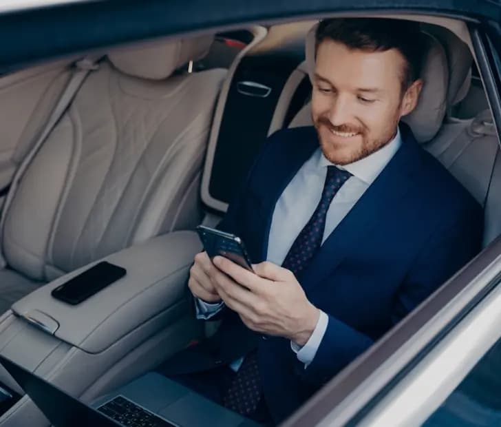 Passenger booking a ride on a phone from the back seat of a luxury car